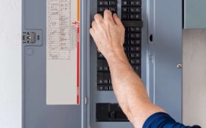 Resetting tripped breaker in residential electricity power panel. Electrician turning off power for electrical outlet at circuit breaker box.