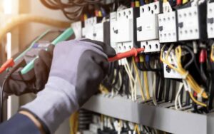 Electrician engineer tests electrical installations and wires on relay protection system. Adjustment of scheme of automation and control of electrical equipment.