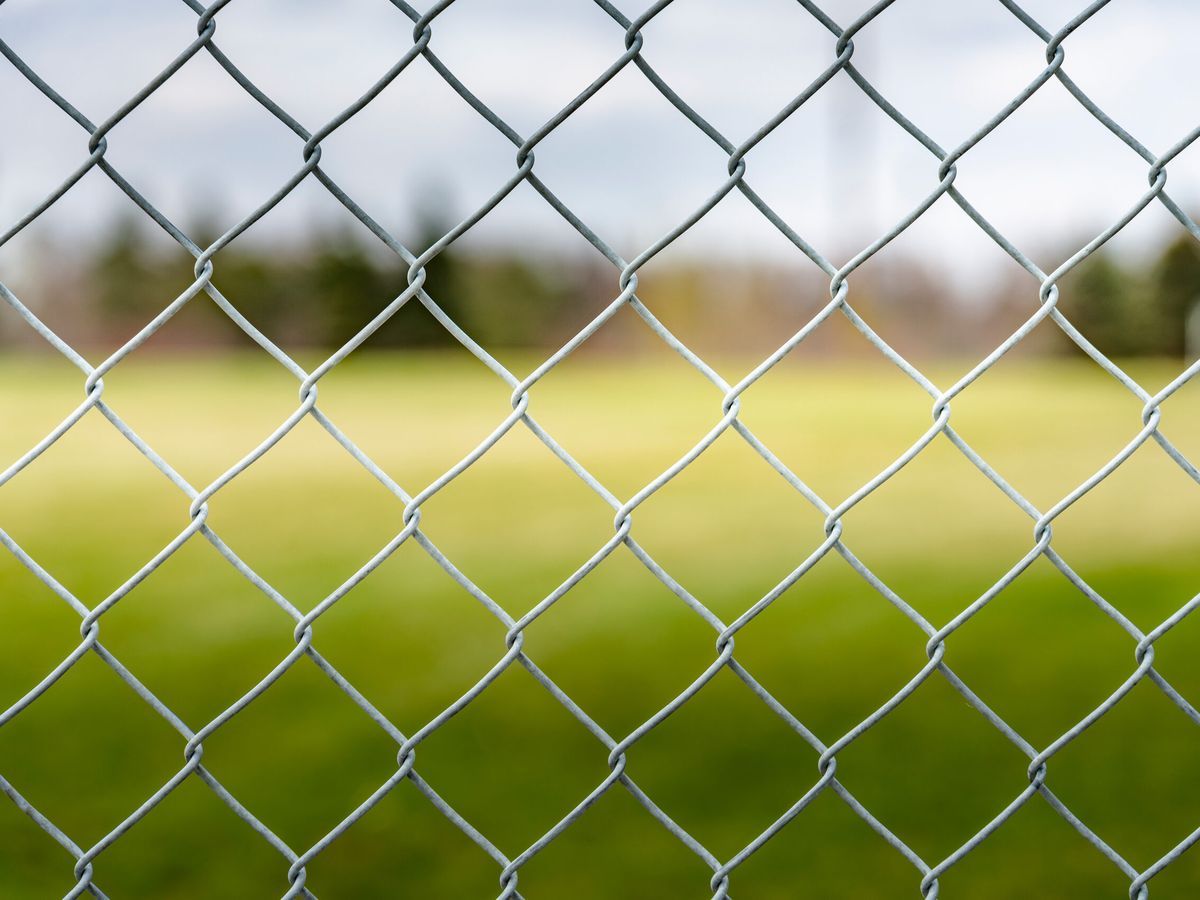 A chain link fence in front of a field